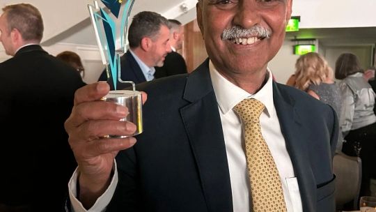 Mike holds his award and smiles