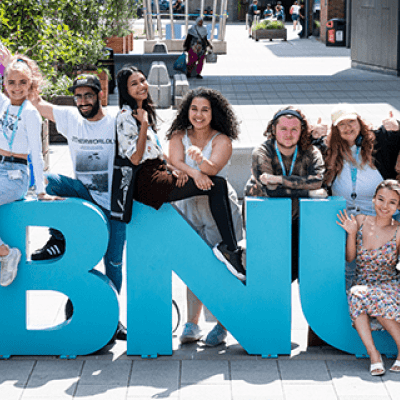 BNU students stood and sat around the BNU letters on the concourse, with their hands up in the air smiling towards the camera