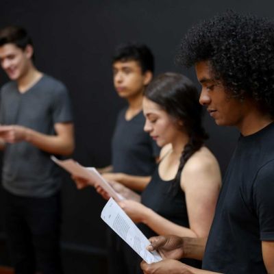 Five students stood in a line reading their scripts in a music class