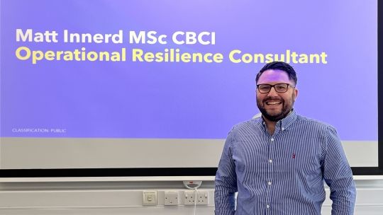 Man standing next to interactive whiteboard smiling. The white board says Matt Innerd MSc CBCI Operational Resilience Consultant