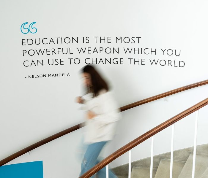 student walking down the stairs in the Gateway building in front of a Nelson Mandela quote