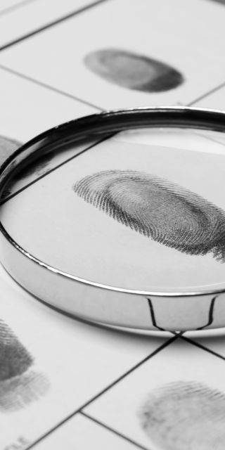 Magnifying glass on top of sheet of thumbprints