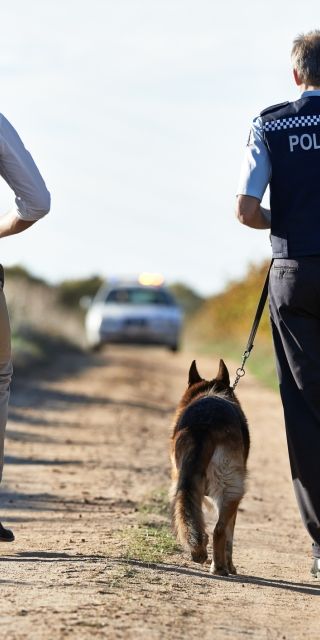 police officers walking together outside with a dog
