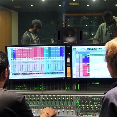 two men looking at two screens in a music studio 