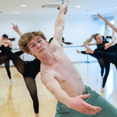 A dance student leading fellow dance students in a choreograph in the dance studios