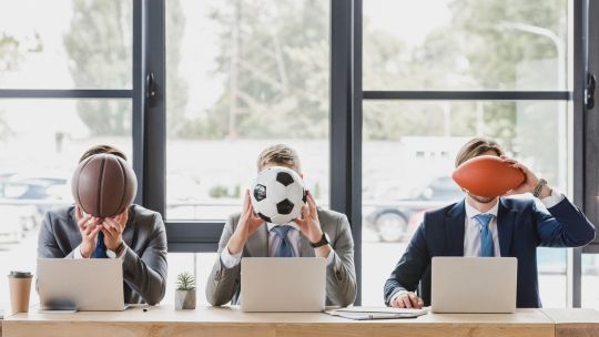 three people holding sports balls against their faces in an office