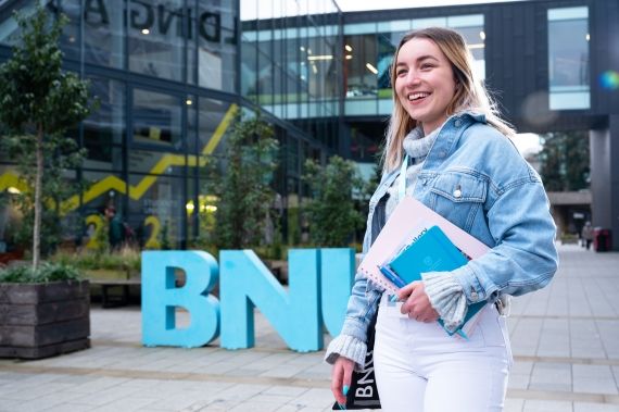 Female student outside the BNU sign at High Wycombe campus