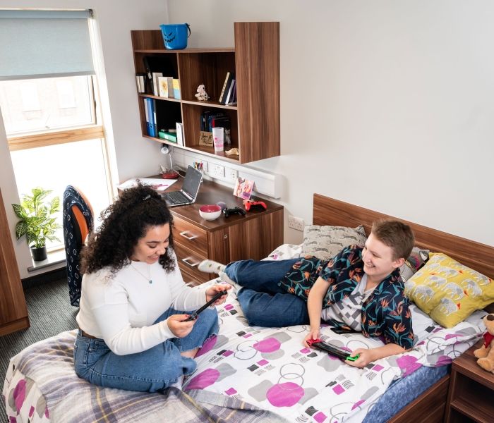 Two female students chatting at one of the bedrooms at Windsor House accommodation
